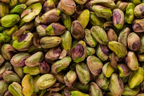 Mnóstwo łuskanych pistacji, zielonych i fioletowych. Czy pies może jeść pistacje? Lepiej nie ryzykować, bo mogą być szkodliwe.