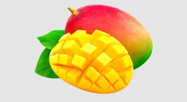 Soczyste mango, pokrojone w kostkę, obok całego owocu. Czy pies może mango? To pytanie nurtuje wielu właścicieli czworonogów.