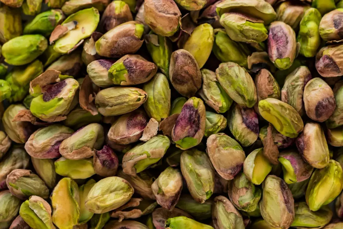 Mnóstwo łuskanych pistacji, zielonych i fioletowych. Czy pies może jeść pistacje? Lepiej nie ryzykować, bo mogą być szkodliwe.